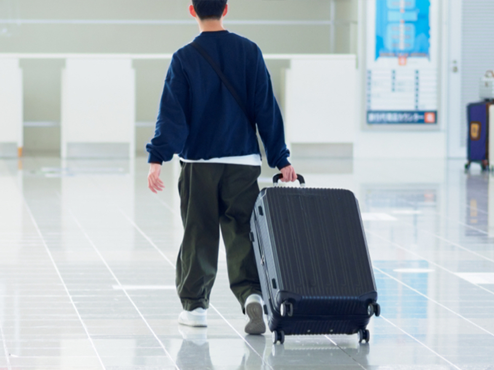 スーツケースを引いて空港を歩く留学生