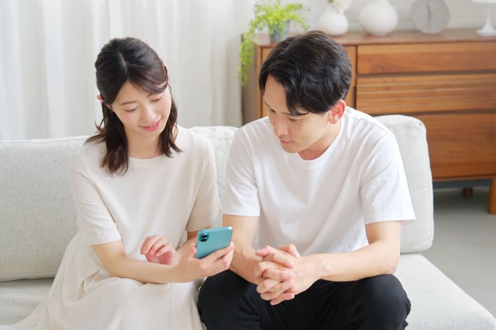 ソファでスマホを見る夫婦