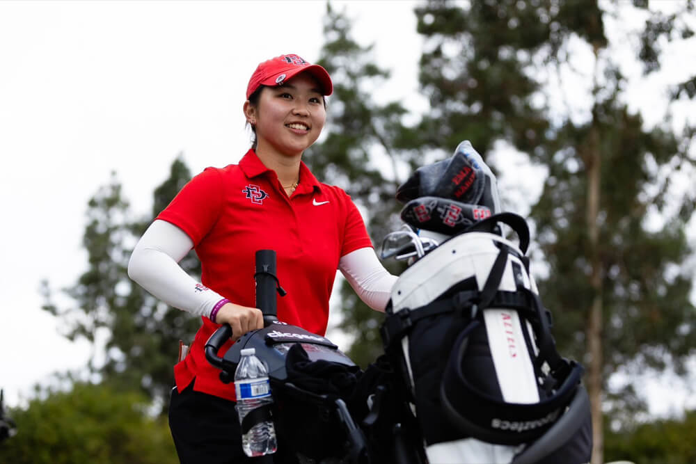 ゴルフカートの横で笑顔を見せるサンディエゴ州立大学女子ゴルフ部の選手