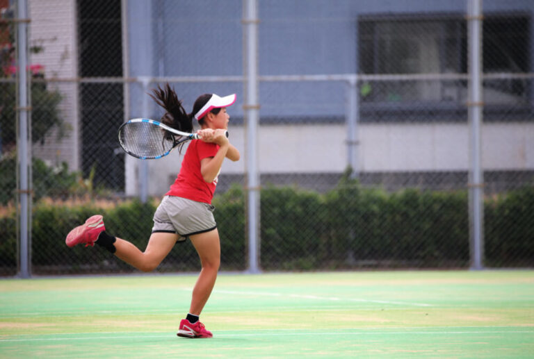 フォアハンドで打ち返す女子テニス選手